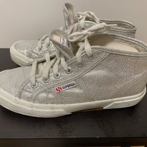 Superga sneakers  - Stl 37,5 Silverglittriga Superga inköpta i London. Använda, dock sparsamt, går att putsa upp det vita och byta snören. 