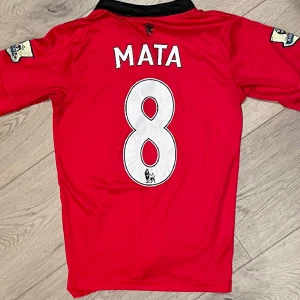 Äkta- Manchester United Hemmaställ 12/13 - Säljer detta äkta Manchester United hemmaställ ifrån säsongen 2012/13, med guldiga Premire League Symbole på armarna, med Juan Mata #8. Storleken är M, men passar även S. Det är bra skick på tröjan, förutom AON loggan som har lostnat lite.Nypris 1200