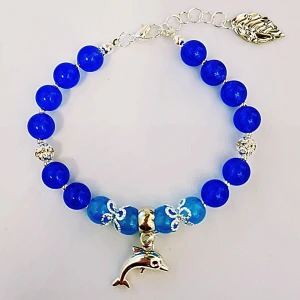 Havsblått armband med delfin - Silvrig delfin och silverdetaljer (ej äkta silver men kan innehålla nickel),  blåa både mörkare och ljusare glaspärlor. Silvrig blingpärla. Justerbart armband. Passar storlekar mellan 16-18cm. 