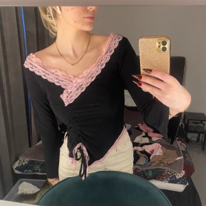 V-ringad långärmad  - Svart v-ringad långärmad med rosa spetsdetaljer och snören som man kan dra åt för syns skull, den har dessutom lite vidare ärmar som man kan se lite på första bilden Skriv om frågor😊 Kolla bio