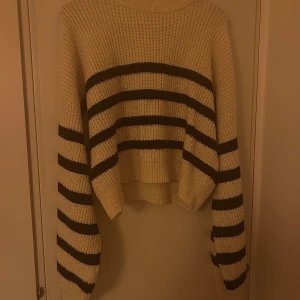 Randig stickad tröja - En beige/vit stickad tröja med svarta ränder. Lite oversized i storleken och är i bra skick.
