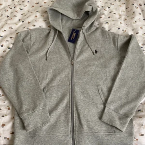 Ralph Lauren zip - En grå och väldigt fin kofta som jag säljer eftersom jag har två likadana. Skicket är prima eftersom den fortfarande är helt ny!