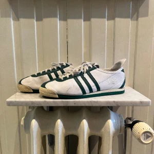 Adidas italia 1960 trainers - Ett par snygga Adidas italia 1960 trainers i vit och grön färg skorna är köpta på 90 talet då det är min pappas skor. Skicket på skorna är 6,5/10 då dom har tappat lite färg här och där men det syns inte när man har på dom. Pris kan diskuteras