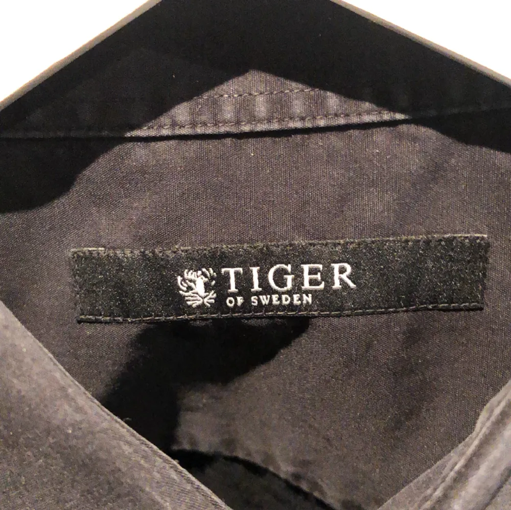 Härlig Tiger Of Sweden skjorta som är svart men i vissa ljus mörblå då det snyggaste med den är en mindre synlig urtvättnad. Storlek L men passar lika bra M. Kom med frågor!. Skjortor.