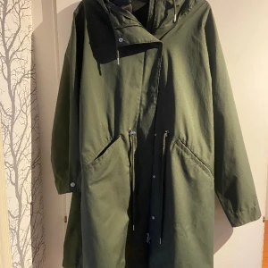 Mörkgrön regnkappa  - Stl XL, rymlig modell, använd max fem ggr, skön textil som är vattentät. Nypris 950:- 