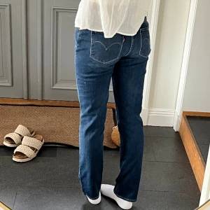 Mörkblå Levis jeans - Mörkblå Levis jeans med rak passform. Storlek 29 och passar mig som är 172 och brukar ha 36 eller S i byxor förutom att de är lite korta. Tvärs över midjan är det 39 cm och innerbenslängden är 78 cm. Fint skick! Använd gärna köp nu!