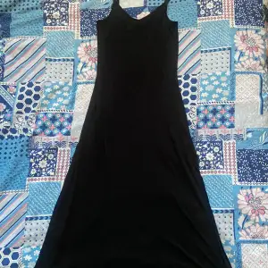 mysig svart långklänning i strechigt tyg, öppningar på sidorna och justerbara band ! Storlek: XS/S Längd:115cm