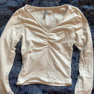 Vit topp - Säljer denna snygga långärmade topp från H&M. Den är använd, men i bra skick. Den är lite nopprig på vissa ställen men det är inget man tänker på. Storlek XS. Säljer för 60kr. 