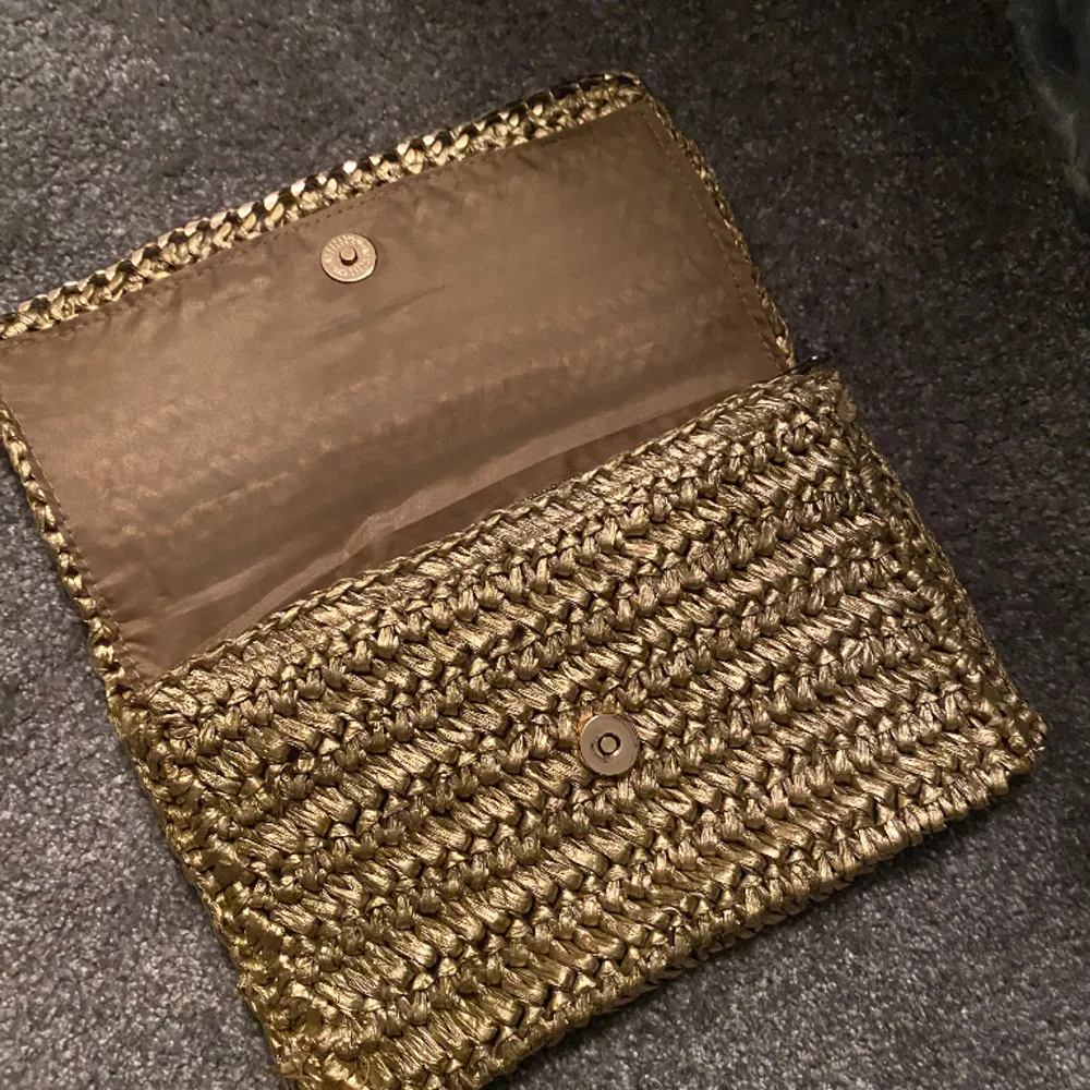Guldig kuvertväska i strå från H&M, helt ny. Väskor.