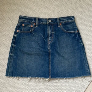 Jeanskjol från Levis - Nyskick. Midjemått ca 72 cm. Längd 38 cm. Hittar inte lapp angående storlek men jag brukar ha xs på kläder. 