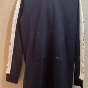 Ny Gant klänning st 176 xs s mjukis - NY Gant mjukis luvklänning. Mörkblå med Gant emblem längst med sidorna . Lappar kvar aldrig använd.  Mysig luva på. Fickapå magen. Från kidsbrandstore. Dottern hade fler och denna blev ej använd. St 176 passar vuxna. St från 164 , 170, 176, xs , s.