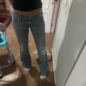 Lågmidjade bootcut jeans - Så snygga lågmidjade bootcut jeans med slitningar och färgprint på! Midjemått 87 cm, midjemått (rakt över) 40cm, innerbensmått 84 cm och ytterbensmått 104 cm 