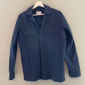 Samsø o samsø overshirt - Fint skick. Mörkblå overshirt (eller iaf skjorta med tjockare/styvare tyg) Bild nr 2 är missvisande färgmässigt. Vet inte varför den blev så gul. Skjorta. Är marinblå som första och sista bilden.