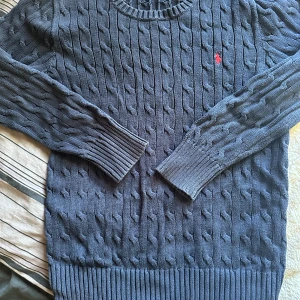 Kabelstickad strl L 14-16 år  - Marinblå kabelstickad till barn i bra skick, strl L (14-16år) men skulle säga att den är liten i storleken.