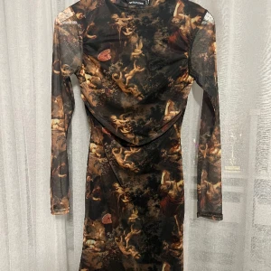 Mini Bodycon PLT dress - En helt ny och oanvänd klänning med detta fina mönster med änglar på. Köpte klänningen för ca ett år sen. Materialet är i mesh och har såklart vanligt tyg under meshen så att man ej ser igenom. 