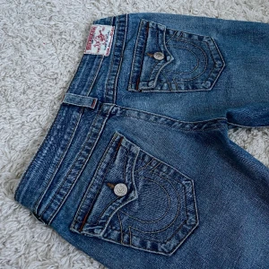 Vintage True Religion Jeans  - Lågmidjad och smått bootcut/straight modell med snygga detaljer. ❤️ Innerben: 79cm, midja rakt över: 36cm. De är uppsydda längst ner för att passa någon runt 165 (som jag). 🫶 Håll koll på min profil, lägger för det mesta upp vintage jeans! 😍