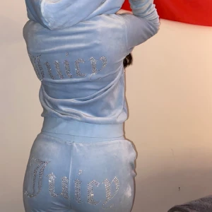 Blå Juicy Couture tracksuit🩵 - Säljer nu mitt andra juicy couture tracksuit som är otroligt snygg & i bra skick!  Har glitter tryck både bak på rumpan och ryggen samt lite ovanför höften.  Byxorna är i storleken Xs och koftan i storleken. Kontakta mig vid intresse, fler bilder mm!