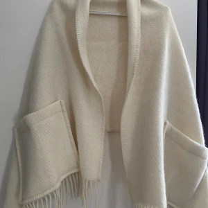 Sjal/kofta lapuan kankurit - Pocket shawl från Lapuan Kankurit säljes i nyskick. One size. Bär denna som en sjal, eller svep den som en filt när kylan tränger på. Företaget värdesätter inte bara god kvalitet utan även hållbar utveckling och materialets spårbarhet.  
