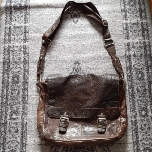 Axelremsväska i äkta läder - Jättefin axelremsväska i äkta mörkbrunt läder med flera fack. Baksidan är blanknött men fin ändå.