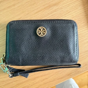 Tory Burch plånbok  - Säljer denna fina Tory Burch plånbok men som även har fack för mobil och kan användas som clutch. Använd fåtal gånger, köpt på NK i Stockholm 