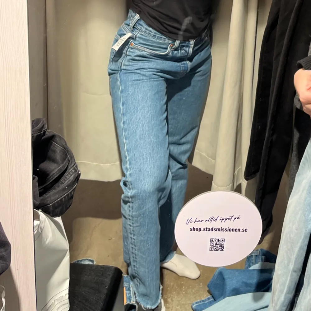 Ett par blå jeansbyxor med klassisk femficksdesign och knappgylf. Byxorna har en rak passform och är tillverkade i denim.. Jeans & Byxor.