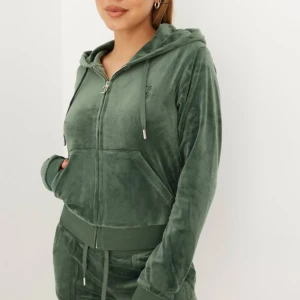 Grön hoodie i velour - En bekväm grön hoodie i velour med dragkedja framtill och huva. Tröjan har långa ärmar och ribbade muddar vid ärmslut och nederkant. JUICY COUTURE, jättebra skick