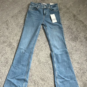 Blå jeans från Zara - Ett par blå jeans från Zara i storlek 36. Jeansen har en klassisk femficksdesign och är tillverkade i denim. De har en knapp och dragkedja framtill. Aldrig använda