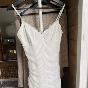 Jättefin vit klänning med rynkat tyg, se bilden. Slutar mitt på låren och är tight och formar kroppen fint. Dubbelt tyg så inte genomskinlig. Jättefin till student, andra avslutningar eller en sommardag. Aldrig använd, endast provad på🥰🥰