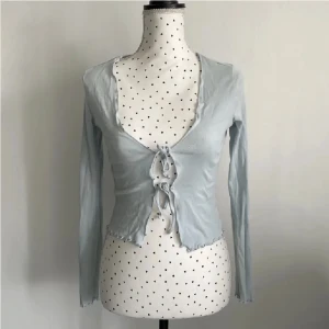 Babyblå knyttop - Ginatricot - En jättegullig topp fran Ginatricot, endast använd EN gång, som helt ny. Original pris 249kr men säljer för 99kr då den inte kommer till användning. Skulle nog säga att det passar alla mellan XS-M för man kan justera själv. Storlek S.