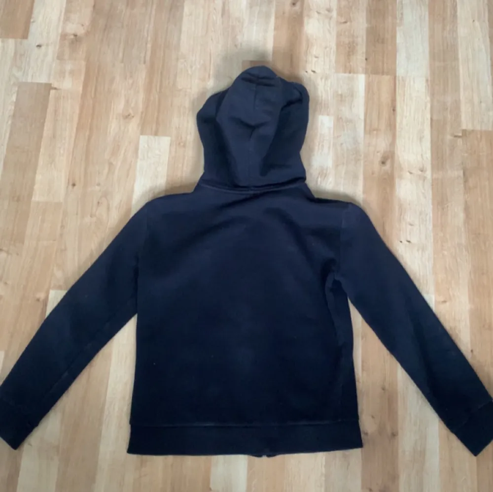Säljer en vanlig svart zip up hoodie. Den är i storlek 134-140 och är i 10/10 i skick. Den är också 80 procent bomull och 20 procent polyester. Den är väldigt simple och Clean när det kommer att göra en outfit med den.. Hoodies.