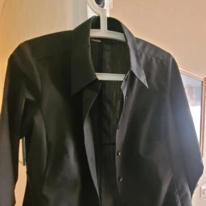 Blus - Fint skick. Liten slits i ärmarna. Kort modell, aningen figursydd. 