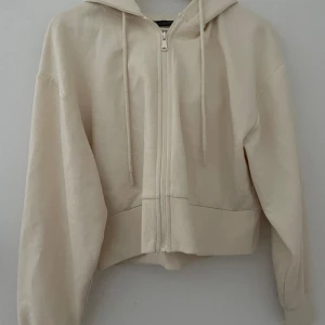 Krämvit Zip hoodie - Skön zip hoodie från Zara i en fin krämvit färg. Lite kortare i längden. Använd en gång