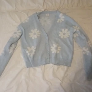 Blå stickad kofta med vita blommor från Lindex - Bra skick, storlek 146/152🩵🤍