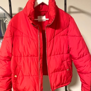 Röd dunjacka med hög krage - Röd dunjacka från Bershka i storlek S. Den har en kortare model (täcker inte rumpan) men med en hög krage vilket är superskönt när det är lite kyligare ute.