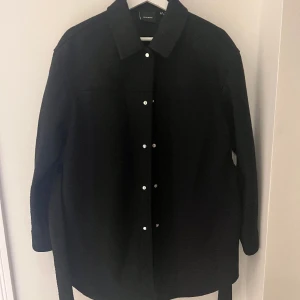 Svart jacka med skärp - Oanvänd. Med skärp och två fickor. Normal i storlek.