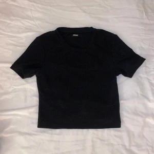 Glittrig t shirt - Fin glittrig t shirt i svart! Den passar perfekt till en enklare fest outfit. Säljer då den inte används.