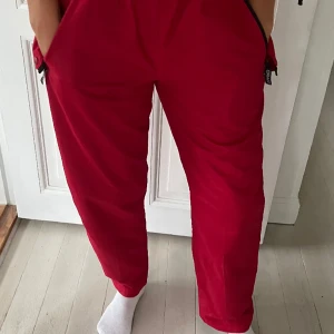 Röda Cargo baggy vintage byxor unika o oanvända - Oanvända röda vintage cargobyxor från Craft  Byxorna är fodrade,med justerbart resår i midjan,spännen nertill . De är inköpta för flera år sedan och går därmed inte att köpa i butik.  Tjejen på bilden har normalt s/m alt38.