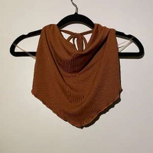 Brunt linne - Detta linnet är format som en triangel nedtill och har lite volanger i kanterna - se bilder. Vid brösten går den ner lite som om tyget är vikt - super snyggt. Bak till är den mycket kortare. Snören som knyts runt halsen. 