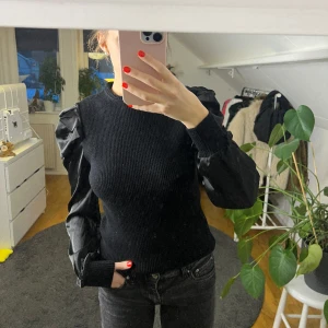 Svart topp - Svart topp med fin krage och puffärmar i satin. Superskönt och lite varmare material. 