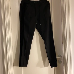 Byxor med resårband i midjan - Fina byxor med resårband i midjan. Sammetsband längs sidorna på byxorna. Fint skick, använd gärna köp nu om du inte har några frågor!
