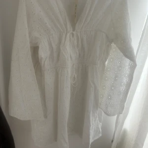 Vit klänning  - En vit klänning från NA-KD, aldrig använd och prislappen sitter kvar. Perfekt nu till studenten eller sommaren.  Storlek 32 men passar även en 34, man kan justera i midjan med snörningarna. 