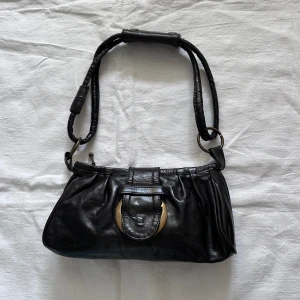 Svart liten väska  - Svart liten väska i äkta läder  Tillverkad i Italien  Bredd 24, höjd 13cm