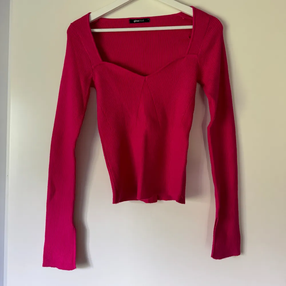 En cerise rosa långärmad tröja med hjärtformad urringning. Den är stickad/ribbad och har slits vid ärmarna. Jätteskönt material, använd 1 gång.. Tröjor & Koftor.