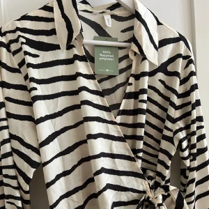 Klänninh - Klänning i siden material med knyte i midjan, prislapp kvar, endast prövad 