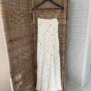Somrig Långklänning  - Vit långklänning med blåa små blommor på. Strl 36, oanvänd med prislapp kvar!