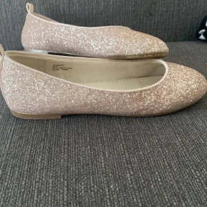 Rosa glittriga ballerina  - Rosa, gulliga och glittriga ballerina. Använt ca 2 ggr max. Lite slitna under skon, inga hål utan bara lite slitna, går fortfarande att använda som vanligt. 