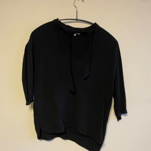 Blus  - Svart blus med knyte i ”halsen”. Viscose material. 