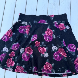 Blommig kjol  - Blommig kjol, svart-rosa, dragkedja bak. 