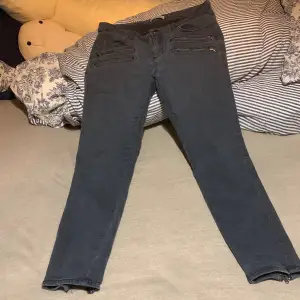 Grå/svarta jeans med dragkedja vid fötterna 