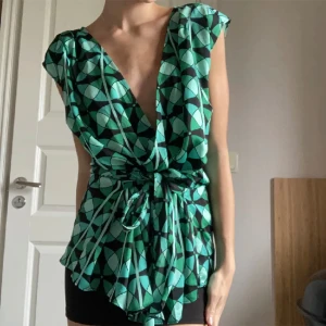 Blus -  Super snygg v-ringad grön blus med olika nyanser av grön, blå och svart. Man kan själv välja att knyta snören till en rosett längst fram eller bak. Köpt från märket Anntaylor. Nyttskick!💚